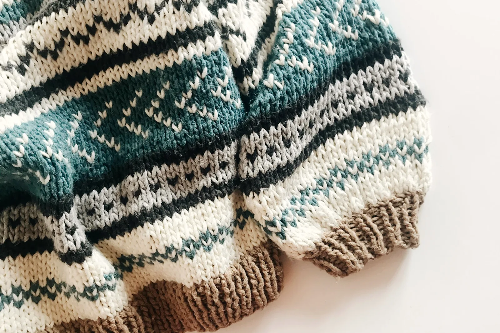 Knitted garments folded in a stack, patterned yokes visible